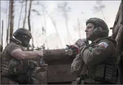  ?? (AP/Alex Babenko) ?? A Ukrainian serviceman from the Azov brigade known by his call sign “Chaos” (right) holds a mortar shell while he waits for a command to fire at a position about a half mile away from Russian forces on the front line in Kreminna, Donetsk region, Ukraine, on Friday.