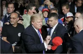  ?? JOHN LOCHER—THE ASSOCIATED PRESS ?? GOP presidenti­al candidate Donald Trump signs a hat after a rally Friday in Novi, Mich.