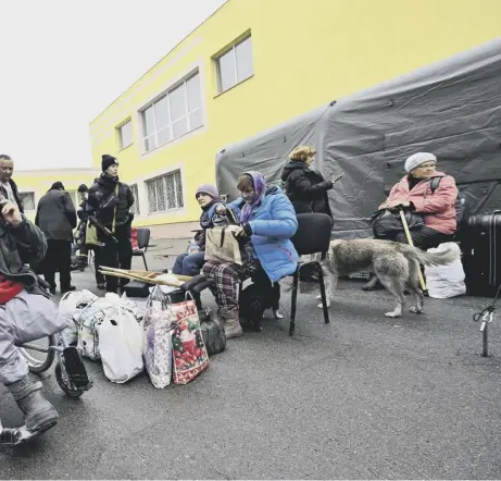  ?? ?? 0 A rescuer assists a disabled man after he was evacuated from the city of Irpin to the outskirts of Ukrainian capital Kyiv last month