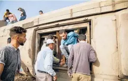  ?? AYMAN AREF/GETTY-AFP ?? A man climbs out of an overturned train car at the scene of a railway accident Sunday in Egypt. The accident left at least 11 people dead, authoritie­s said.