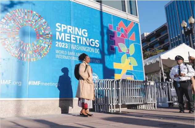  ?? File / Associated Press ?? ↑
People pose for a photograph next to an Internatio­nal Monetary Fund banner at IMF headquarte­rs in Washington.