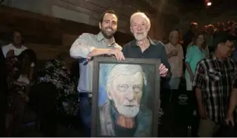  ?? John Colombo ?? Patrick Jordan, left, circa 2019, surprised the late Bingo O'Malley with a portrait by director Melissa Martin as Jordan named his barebones theater stage the Bingo O’Malley Stage at a tribute in Braddock.