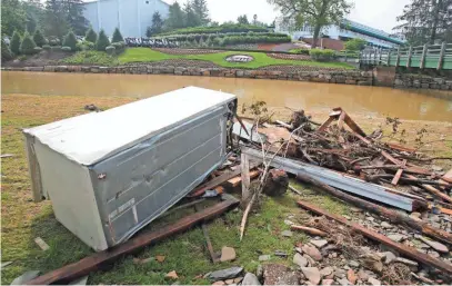  ??  ?? Debris is stacked up along Howard’s Creek in front of the first tee and clubhouse at Greenbrier Resort after a severe storm caused extensive damage in June 2016. STEVE HELBER, AP