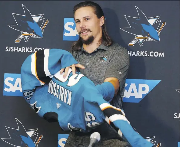  ?? JOSIE LEPE/THE ASSOCIATED PRESS ?? Newly acquired San Jose Sharks defenceman Erik Karlsson puts on a Sharks jersey for the first time Wednesday.