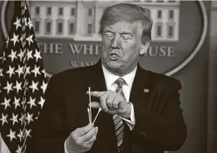  ?? Tasos Katopodis / Getty Images ?? President Donald Trump holds up swabs as he speaks at the daily coronaviru­s briefing at the White House on Sunday in Washington, D.C. “Swabs are easy,” Trump said.