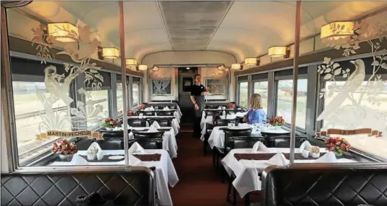  ?? JANET PODOLAK — THE NEWS-HERALD ?? The dining car aboard Via Rail’s Canadian is decked in white tablecloth­s and defined by etched glass panels. Here, a lunch-lingering passenger talks with a dining car attendant.