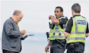  ??  ?? A man being issued with an on-the-spot fine for allegedly breaking lockdown rules in Edinburgh, left, while a man fishing on Brighton beach is told to move on, below