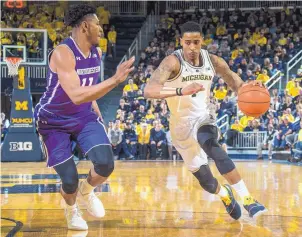  ?? TONY DING/ASSOCIATED PRESS ?? Michigan guard Charles Matthews attempts to drive past Northweste­rn guard Anthony Gaines during the second half.