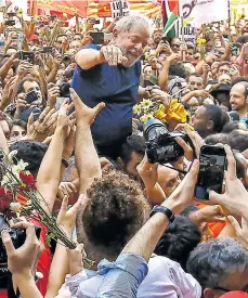  ??  ?? Decenas de militantes alzan en hombros en Sao Paulo a Lula da Silva, en el momento que se disponía trasladars­e al aeropuerto.