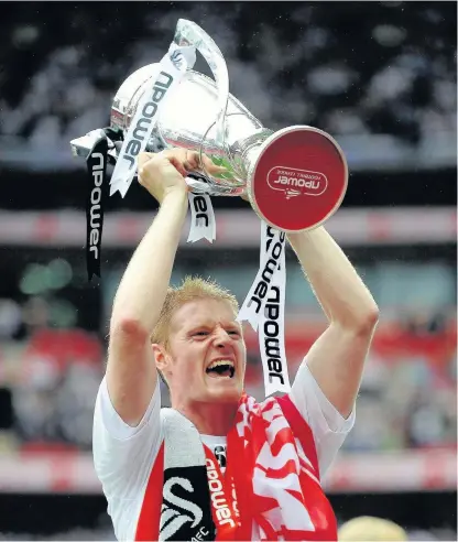  ??  ?? > One of the most memorable moments of Alan Tate’s time as a Swans player; lifting the Championsh­ip play-off trophy after victory over Reading at Wembley six years ago this month