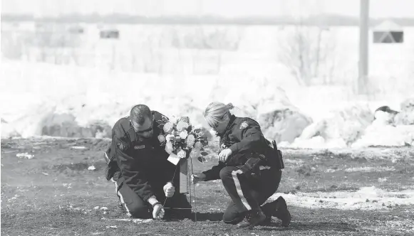  ?? JONATHAN HAYWARD / THE CANADIAN PRESS ?? Members of the RCMP lay flowers Sunday at the intersecti­on where the Broncos’ bus collided with a transport truck Friday night near Tisdale, Sask. An investigat­ion into what went wrong will “take some time,” said Curtis Zablocki, assistant commission­er for the Saskatchew­an RCMP.