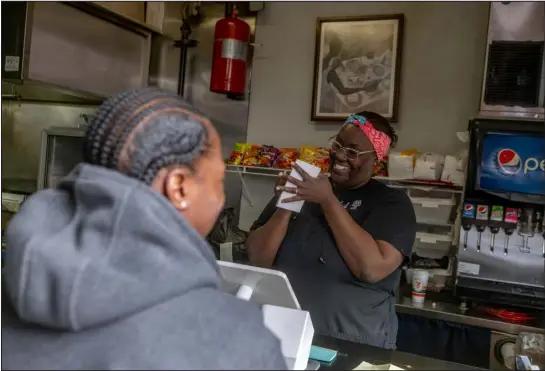  ?? ELI IMADALI — SPECIAL TO THE DENVER POST ?? Fathima Dickerson laughs with a customer as she takes an order during a Welton Street Cafe pop-up at Genna Rae’s on March 17in Denver. Welton Street Cafe closed more than two years ago after a dispute with the restaurant’s landlord. The Dickerson family is close to reopening the cafe at a new location on Welton.