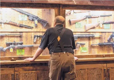  ?? LISA MARIE PANE/ASSOCIATED PRESS ?? A man looks at cases of firearms in April in the halls of the Indianapol­is Convention Center. The National Rifle Associatio­n held its 148th annual meeting in the center.