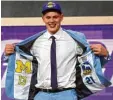  ?? Foto: dpa ?? Moritz Wagner zeigt mit den Logos von Alba Berlin und den Michigan Wolveri nes, wo seine Wurzeln liegen.