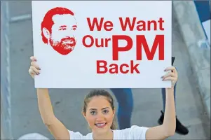  ?? AP PHOTO ?? A Lebanese woman holds a placard supporting the outgoing Lebanese Prime Minister Saad Hariri to return from Saudi Arabia during the Beirut Marathon, in Beirut, Lebanon, Sunday.