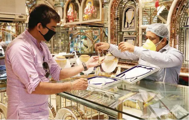  ?? Reuters ?? ↑
A salesman shows gold necklaces to a customer at a jewellery showroom in Kolkata on Friday.