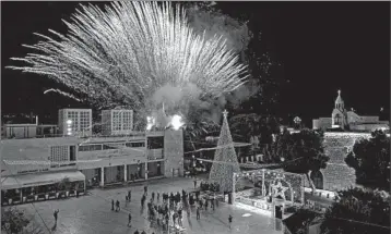  ?? EMMANUEL DUNAND/GETTY-AFP ?? A fireworks display is set off Saturday during the lighting of the Christmas tree in the biblical city of Bethlehem. Only a few dozen people attended the ceremony near the Church of the Nativity, where Christians believe Jesus was born. Others watched it online due to the coronaviru­s pandemic. The annual event normally draws thousands of pilgrims.