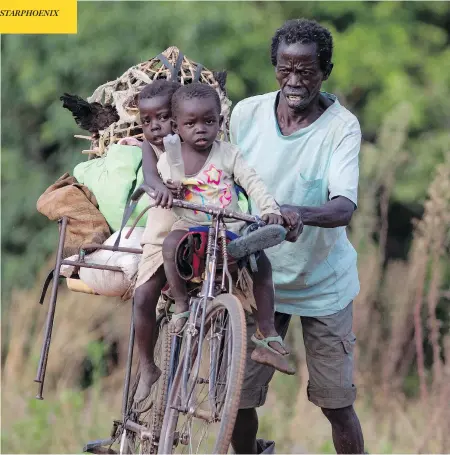  ?? DAN KITWOOD / GETTY IMAGES ?? A man pushes his bicycle carrying his two children after crossing from South Sudan into Uganda earlier this year. Since August 2016, about 1.8-million South Sudanese have fled abroad. More than half of them ended up in Uganda.