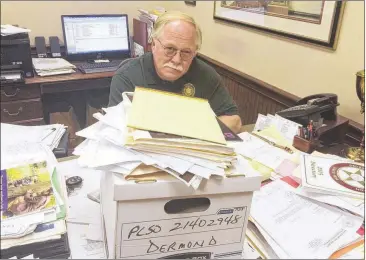  ?? CHRISTIAN BOONE / CBOONE@AJC.COM ?? Putnam County Sheriff Howard Sills inspects documents related to the murders of Russell and Shirley Dermond. Russell Dermond’s body was discovered in the garage of his Lake Oconee home. Ten days later, two fishermen discovered his wife’s body floating...