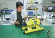  ?? PROVIDED TO CHINA DAILY ?? Fan Ping, chief technology officer at Qingdao Robotfish Marine Technology Co Ltd, debugs the Coral Guard robot.