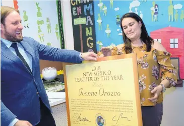  ?? GREG SORBER/ JOURNAL ?? Christophe­r Ruszkowski, New Mexico Education Secretaryd­esignate, presents Ivonne Orozco with a plaque recognizin­g her as the 2018 New Mexico Teacher of the Year in her classroom at the Public Academy for the Performing Arts on Tuesday afternoon.