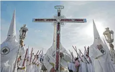  ?? FOTOS: DPA ?? Das imposante Silberkreu­z „Cruz de Guía“wird bei der Palmsonnta­gsprozessi­on durch Sevilla getragen – der Auftakt der Semana Santa.