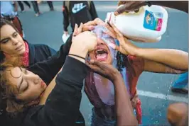  ?? Jason Armond Los Angeles Times ?? SHORTLY AFTER curfew in Minneapoli­s on May 30, a protester gets help rinsing her eyes after being pepper-sprayed by law enforcemen­t officers.