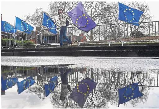  ?? — Reuters ?? Reflecting on a referendum: An anti-Brexit protester is reflected in a puddle as she walks near the Houses of Parliament, London.