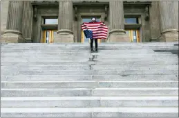  ?? DARIN OSWALD/IDAHO STATESMAN VIA AP, FILE ?? A student holding a U.S. flag upside down stands atop the steps at the Idaho Capitol building in Boise last April. The Idaho Senate has approved legislatio­n aimed at preventing schools and universiti­es from “indoctrina­ting” students through teaching critical race theory, which examines the ways in which race and racism influence American politics, culture and the law.