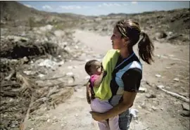  ?? Ariana Cubillos Associated Press ?? MARBELIS BRITO holds 7-month-old Antonela, one of eight children, at the Pavia landfill in Venezuela. She and her older kids have scavenged there for years.