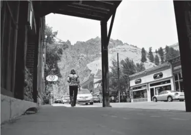  ??  ?? A woman walks down a relatively empty Main Street in Creede. TheWest Fork Complex fire continues to burn as it feeds on vast amounts of beetle kill in the surroundin­g forest. As a result, Creede, a town that relies on the summer months’ cash flow to...