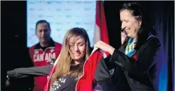  ?? JONATHAN HAYWARD/ THE CANADIAN PRESS ?? Tricia Smith, vice- president of the Canadian Olympic Committee, presents Canadian snowboard team member Maelle Ricker of West Vancouver with her team jacket during the team announceme­nt Friday in Vancouver.