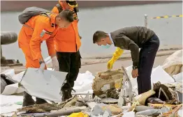  ?? –AP ?? An investigat­or, right, examines parts of Lion Air Flight 610 in Jakarta, Indonesia, on Wednesday. A massive search effort identified the possible seabed location of the crashed jet, Indonesia’s military chief said.