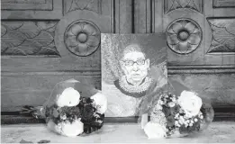  ?? ERIN SCHAFF/THE NEW YORK TIMES ?? A portrait of Justice Ruth Bader Ginsburg is left Saturday against the doors of the Supreme Court. Ginsburg, who died Sept. 18 at 87, led the liberal wing of the court.