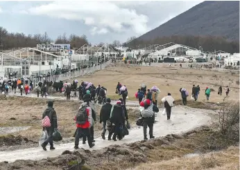  ?? AP Photo/Kemal Softic ?? ■ On Wednesday, migrants walk back to the Lipa camp outside Bihac, Bosnia, after hundreds failed to be relocated from the burnt-out tent camp in the northwest of the country. The migrants were supposed to be transferre­d on Tuesday from the much-criticized Lipa camp to a new location in the central part of the country, but have instead spent some 24 hours in buses before being told on Wednesday afternoon to disembark and return to the now empty camp site.