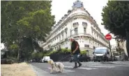  ?? AP PHOTO/FRANCOIS MORI ?? A man walks his dog next to an apartment building owned by Jeffrey Epstein in the 16th district in Paris.