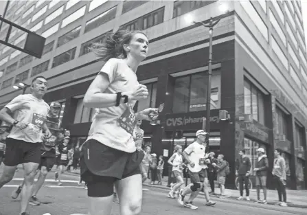  ?? LIZ DUFOUR/CINCINNATI ENQUIRER ?? Runners make their way down Seventh Street during the 2022 Flying Pig Marathon in downtown Cincinnati on Sunday. The marathon runners wore the pink bibs and the half-marathon runners wore green bibs.