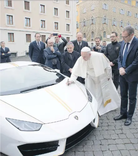  ?? OSSERVATOR­E ROMANO/AFP- GETTY IMAGES ?? Pope Francis signs a Lamborghin­i Huracan received as a gift, as Lamborghin­i CEO Stefano Domenicali, second from right, looks on. Proceeds from the sale of the car will be used to help global charities, including one in Iraq.