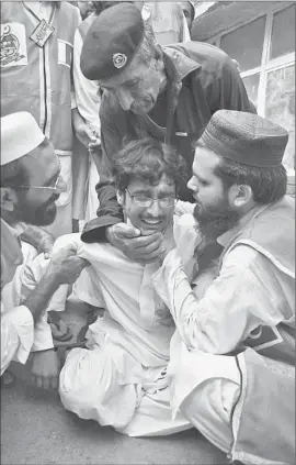  ?? Mohammad Sajjad ?? HEALTH WORKERS in Peshawar comfort a man whose relative was killed in the bombing in Pakistan. Two people died and at least a dozen were wounded.