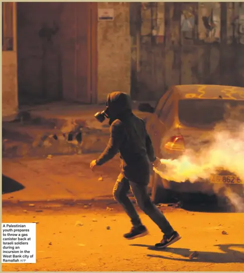  ?? AFP ?? A Palestinia­n youth prepares to throw a gas canister back at Israeli soldiers during an incursion in the West Bank city of Ramallah