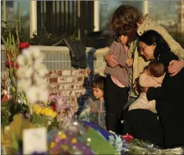  ?? ASHLEY LANDIS — THE ASSOCIATED PRESS FILE ?? A family gathers on Tuesday at a memorial outside the Star Ballroom Dance Studio in Monterey Park, the site of a mass shooting. In the course of 48hours, two gunmen went on shooting rampages at both ends of California that left 18dead and 10wounded.