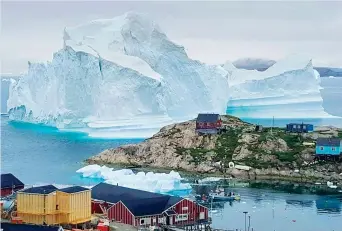  ??  ?? Il pericolo La foto del gigantesco iceberg davanti al villaggio di Innaarsuit, in Groenlandi­a, scattata da Karl Petersen
