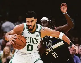  ?? Charles Krupa / Associated Press ?? Boston Celtics forward Jayson Tatum (0) tries to pivot around Milwaukee Bucks guard Jrue Holiday during the first half of Game 5 of an Eastern Conference semifinal Wednesday in Boston.