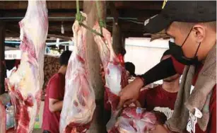  ??  ?? Peserta bergotong-royong melapah daging lembu sebagai persiapan menjamu penduduk kampung.