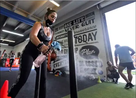  ?? AP PHOTO/WILFREDO LEE ?? Giannina Nicoletti sanitizes a piece of equipment as she works out, Aug. 31, at Legacy Fit in the Wynwood Art District of Miami.