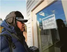  ?? Kathy Willens / Associated Press ?? Ben Chang, of the Queens borough of New York, reads a closure sign posted on the back door of the Visitor's Center at Jamaica Bay Wildlife Refuge on Thursday as a partial government shutdown shuttered some facilities in the New York area.