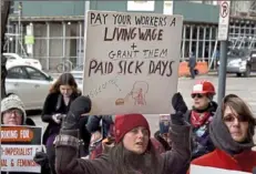  ?? Darrell Sapp/ Post- Gazette ?? Shannon Tomanovich, of Lawrencevi­lle, holds a sign advocating a living wage and sick leave during the Pittsburgh Internatio­nal Women's Strike in March 2018, Downtown.