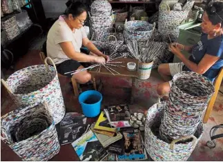  ?? REUTERS ?? Workers from the Risen Christ Parish multi-purpose cooperativ­e roll strips of recycled magazines that will be used to weave baskets in Tondo, Manila yesterday, World Environmen­t Day. The baskets, priced from P200 to P1,000, are exported to Australia,...