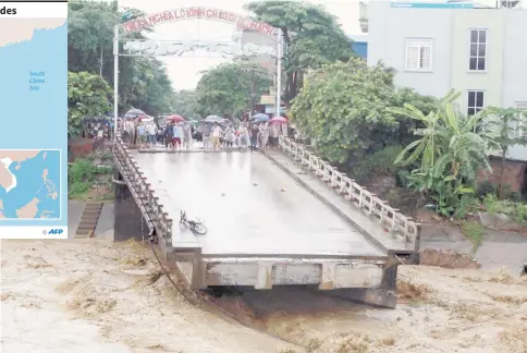  ??  ?? This picture from the Vietnam News Agency shows residents standing at an end of a destroyed bridge in the northern province of Yen Bai. — AFP photo