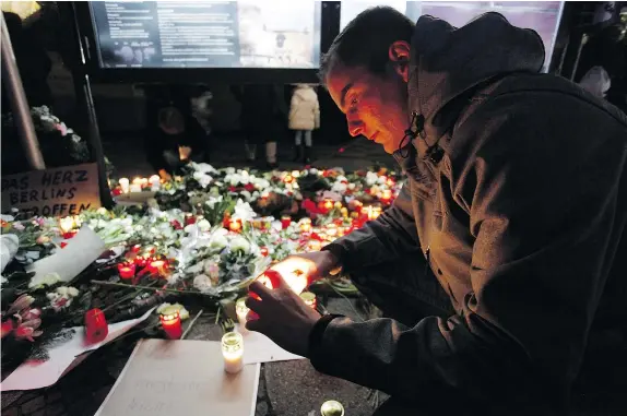  ?? — GETTY IMAGES ?? People leave flowers and candles at a Christmas market in Berlin after a truck plowed through its stalls on Monday evening, killing 12 people and injuring 48. German police are hunting for the driver of the truck, who fled after the attack.